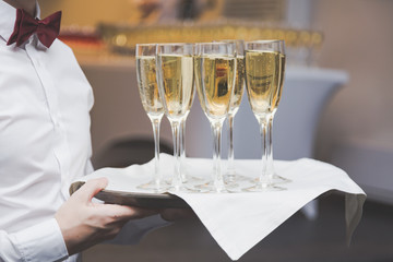 Waiter serving champagne glasses on a tray in a restaurant.