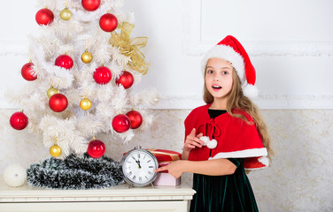 Girl kid santa hat costume with clock counting time to new year. How much time before. Last minute...