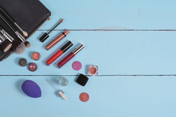 topview of set of different make up cosmetics and brushes on wooden blue background. Texture. flat...