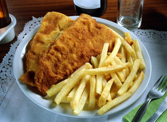Plato combinado con dos trozos de merluza rebozados y patatas fritas.