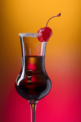 Alcohol layered shot cocktail garnished with cherry .