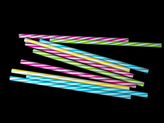 Piles of colorful striped plastic drinking straw, black underground