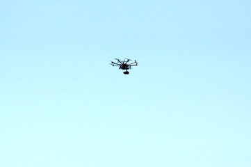 Unmanned aerial vehicle - quad copter with a camera and video transmission soars in the turquoise sky.