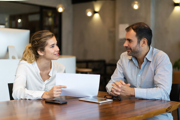 Positive young employee showing report to business colleague. Business man and woman working on...