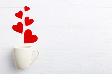 Red hearts coming out of the cup on white background. Concept of Women's Valentine's Day. Place for text, copy space.