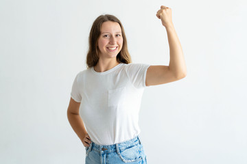 Cheerful young woman pumping fist and celebrating achievement. Pretty girl looking at camera. Achievement concept. Isolated front view on white background.