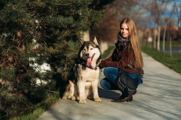 A smiling girl is walking with a dog along the embankment. Beautiful husky dog