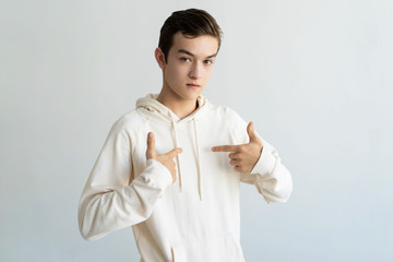 Serious teen boy pointing at himself. Young man looking at camera. Self-reliance concept. Isolated front view on white background.