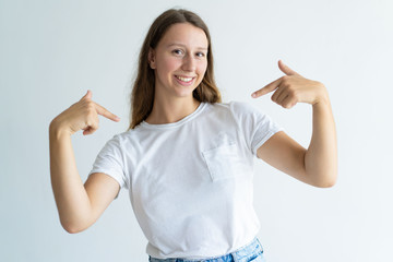 Smiling lovely young woman pointing at herself. Pretty lady looking at camera. Self-reliance concept. Isolated front view on white background.