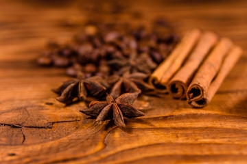 Pile of the coffee beans, star anise and cinnamon sticks on wooden table