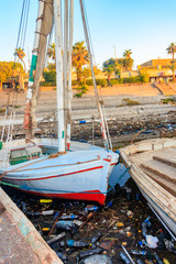 Fototapeta na wymiar Old boats moored in dirty harbour. Pollution of river, sea, ocean water with waste, plastics garbage. Concept of pollution of ocean, sea and river coastline with plastic trash