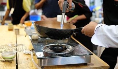 chef cooking food in pan & grilling by fire from mini blow torch