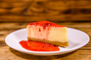 White plate with cheesecake New York and raspberry jam on wooden table