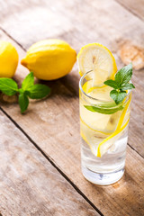 Lemon water with fresh lemons and green mint on table