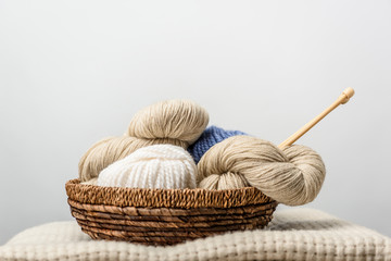 Fototapeta na wymiar close up view of yarn with knitting needles in wicker basket on grey backdrop