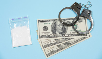 A bag of drugs, US dollars and handcuffs on the table.