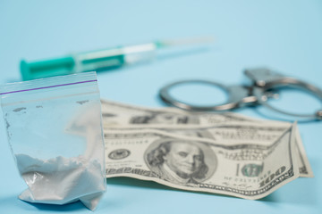 A bag of drugs, US dollars and handcuffs on the table.