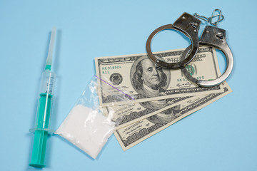A bag of drugs, US dollars and handcuffs on the table.