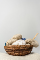 Fototapeta na wymiar close up view of yarn clews in wicker basket on grey backdrop