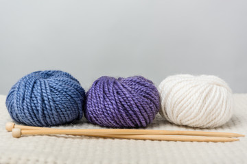 Fototapeta na wymiar close up view of arranged yarn balls and knitting needles on grey backdrop