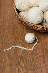 close up view of knitting balls in wicker basket on wooden tabletop