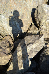 human shadow on large sea stones