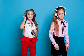 two girls are listening to music with headphones and dance