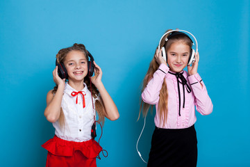 two girls are listening to music with headphones and dance