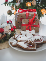 Christmas gingerbreads, candles, and Christmas bell. In background Christmas tree.