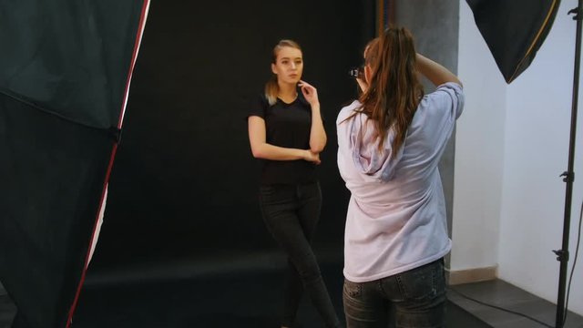 Young woman models having a photo session in the studio. Taking the snaps. Shooting backstage