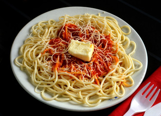 Plato de espaguetis a la carbonara y con un trozo de mantequilla.