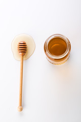 Fresh honey. Honey in glass jars with stick on white background.