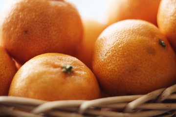 ripe bright tangerines in the peel lie in the basket, lit by the soft sun