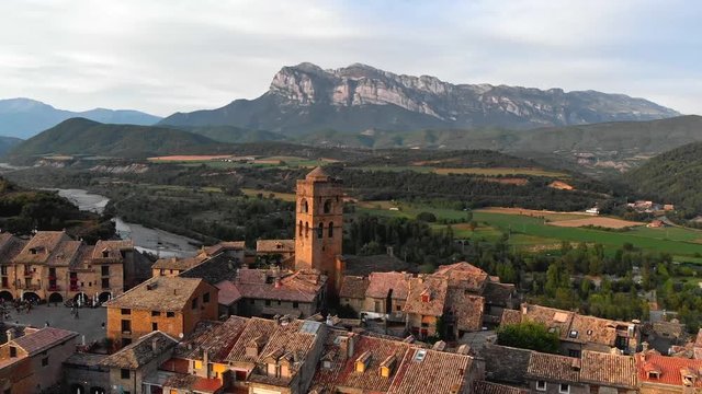 Flying over Ainsa, Spain with mountains Pena Montanesa in the background during sunset. Ainsa is a town in Aragon in the south of Pyrenees. Aerial shot