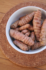 Turmeric rhizome in a bowl on wooden table. Curcuma longa with selective focus
