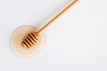 Top view of honey and honey dipper on white background