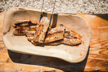 Delicious grilled pork bacon on the traditional wooden dish on the old wooden table
