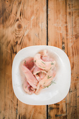 Fresh organic chicken meat on white dish with rosemary on the wooden table