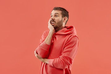 Fototapeta premium I'm afraid. Fright. Portrait of the scared man. Business man standing isolated on trendy coral studio background. male half-length portrait. Human emotions, facial expression concept