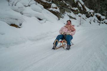 Fototapeta na wymiar Frau fährt mit Schlitten im Schnee auf einer Rodelbahn talwärts