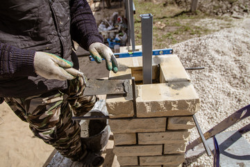 The worker is laying bricks on the fence