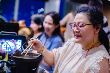 Asian woman is using chopsticks to chop noodle