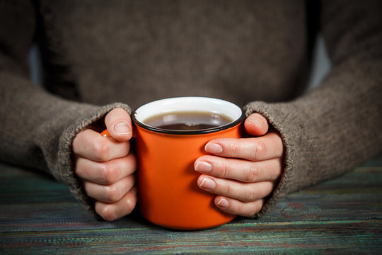 Woman holds a cup of hot tea. Cozy morning at home.