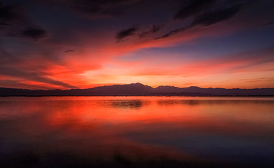 Fototapeta na wymiar Lake view evening of colorful red cloudy sky above the hill with reflection on the water, sunset at Kwan Phayao Lake, Phayao Province, northern of Thailand.