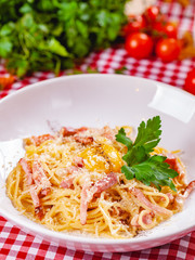 Spaghetti Carbonara with bacon, yolk and cheese on white plate. Close up