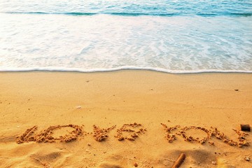 Valentine's Day concept, the word love you writing on sand beach with blue waves ocean.