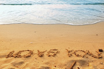Valentine's Day concept, the word love you writing on sand beach with blue waves ocean.