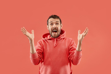 Wow. Attractive male half-length front portrait on coral studio backgroud. Young emotional surprised bearded man standing with open mouth. Human emotions, facial expression concept. Trendy colors - obrazy, fototapety, plakaty