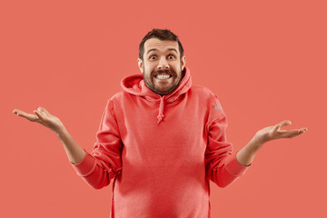 Fototapeta premium Wow. Attractive male half-length front portrait on coral studio backgroud. Young emotional surprised bearded man standing with open mouth. Human emotions, facial expression concept. Trendy colors