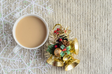 A Cup of coffee with milk , decorated snowflakes and Christmas toy on a light wool sweater.Winter concept.